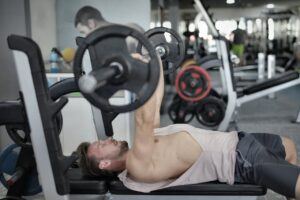 Strong sportsman doing bench press during workout in modern gym