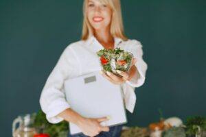Woman Holding a Bowl with Salad and Smiling 