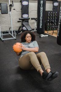 Black overweight woman exercising with ball