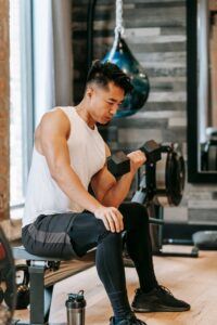 Fit Asian man exercising with dumbbell in gym