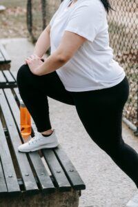 Faceless lady stretching legs on bench in street
