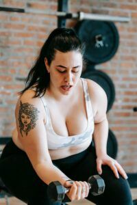 Young Woman Exercising with Dumbbells at the Gym